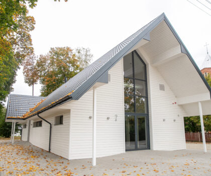 Moderni A formos atsisveikinimo salė Zapyškyje su balta fasado apdaila ir įėjimu